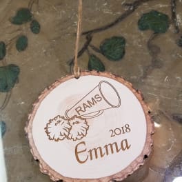 Round wooden ornament with engraved text hanging by twine
