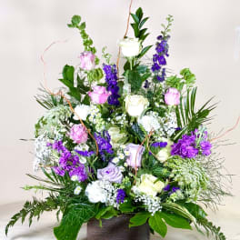 Tall mixed bouquet of roses and purple flowers in a wooden box