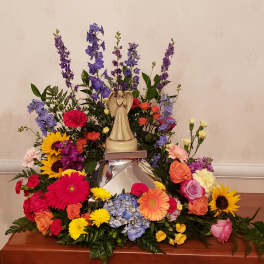 Colorful floral arrangement with an angel figurine on a reflective base