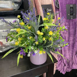 Purple and yellow floral arrangement in a lavender vase