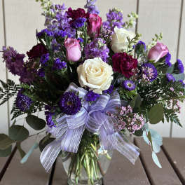 Bouquet of purple and pink flowers with white roses in a glass vase