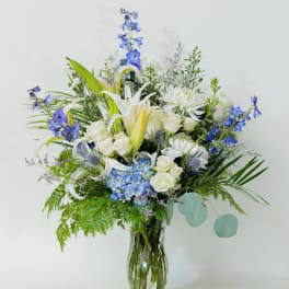 Blue and white mixed flower arrangement in a glass vase