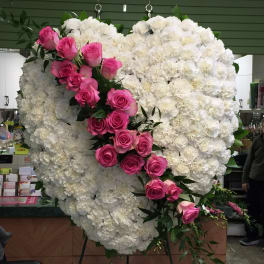 Heart-shaped white floral arrangement with a diagonal spray of pink roses