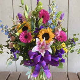 Colorful mixed bouquet in a glass vase with a purple ribbon