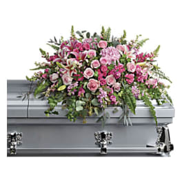Pink and white floral casket spray on a silver casket