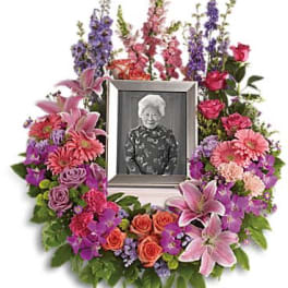 Floral memorial wreath around a framed photo with pink and purple flowers