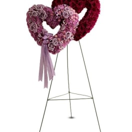 Two heart-shaped floral wreaths on stands, one with a ribbon tail