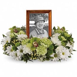 White and green sympathy floral arrangement with a framed photo centerpiece