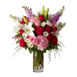 Mixed bouquet of red and pink roses with lilies in a clear glass vase