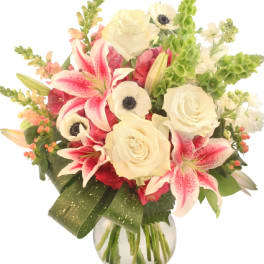 Bouquet of white roses, pink lilies, and white anemones in a glass vase
