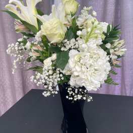 White lilies and hydrangeas in a black vase