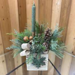 Small evergreen candle arrangement in a wooden box with pinecones and a teal taper candle