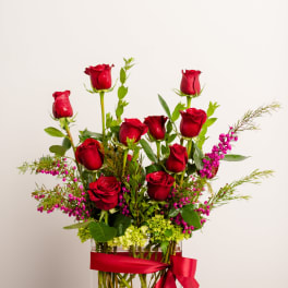 Red roses in a clear square vase with a red ribbon