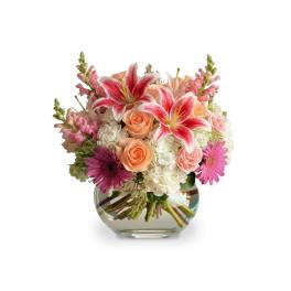 Pink and peach mixed flowers in a round glass vase