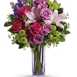 Bouquet of pink and purple flowers in a tall glass vase