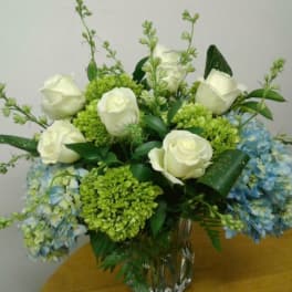 White roses and blue hydrangeas in a clear glass vase