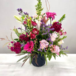 Mixed pink and purple flower arrangement in a dark vase