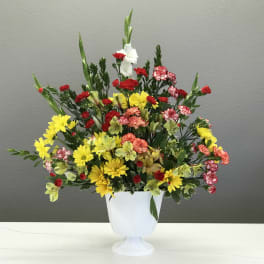 Colorful mixed flower arrangement in a white pedestal vase