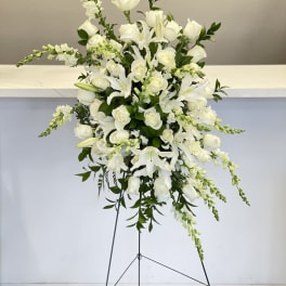 Tall white floral standing arrangement with roses and lilies on a metal easel
