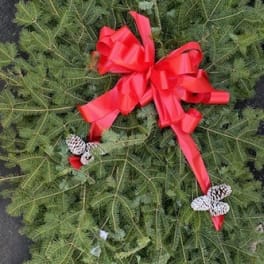 Green holiday wreath with pinecones and a red bow