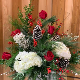 Holiday arrangement with red roses, white hydrangeas, pinecones, and berries