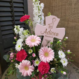 Pink and white floral arrangement with a cross-shaped sign