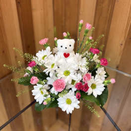 White daisies and pink carnations with a small teddy bear centerpiece
