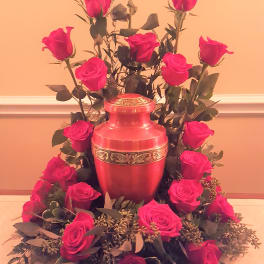 Pink roses arranged around a red urn-shaped vase