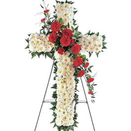 Floral cross on a stand with white flowers and red carnations