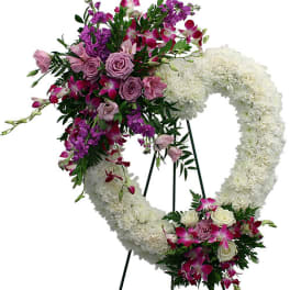 Heart-shaped white floral wreath on an easel with pink and purple flowers