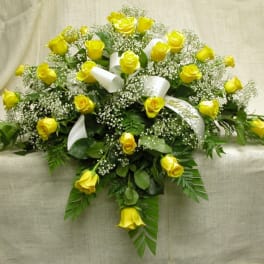 Yellow roses arranged with baby's breath and white ribbon on a draped cloth