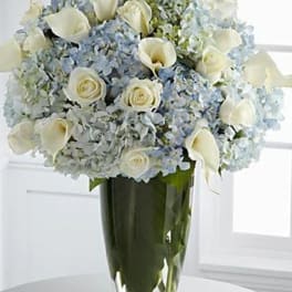 White roses and calla lilies in a tall glass vase