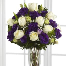Purple and white rose bouquet in a clear glass vase