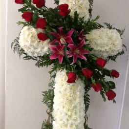 Cross-shaped floral standing spray with white blooms, red roses, and pink lilies
