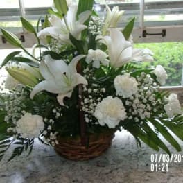 White lilies and carnations in a wicker basket arrangement