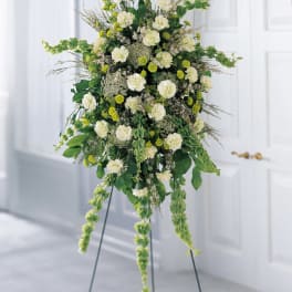 Tall white and green floral standing arrangement on a metal easel