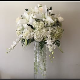 White floral arrangement with lilies and hydrangeas in a tall clear vase