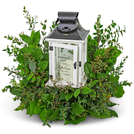 White lantern centerpiece surrounded by green foliage