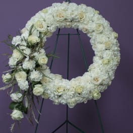 White floral funeral wreath on a green stand