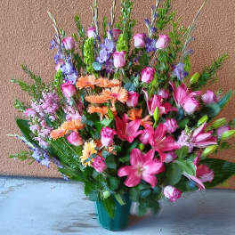 Large mixed bouquet of pink, purple, and orange flowers in a green vase