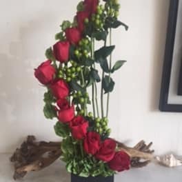 Tall arrangement of red roses in a black vase