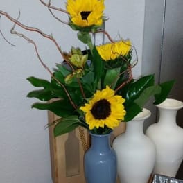 Sunflowers arranged in a blue vase with curly branches