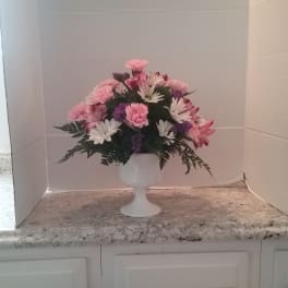 Pink and white flower arrangement in a white pedestal vase