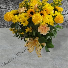Yellow roses and daisies arranged with peach carnations and a ribbon bow