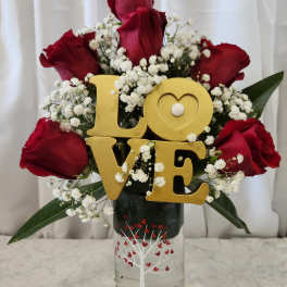 Red roses with baby's breath and a gold LOVE sign in a glass vase