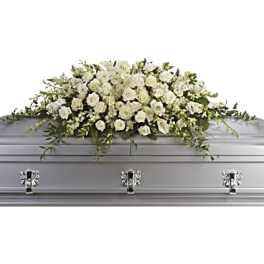 White floral casket spray on a silver casket