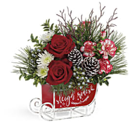 Red roses and white flowers in a red sleigh-shaped container