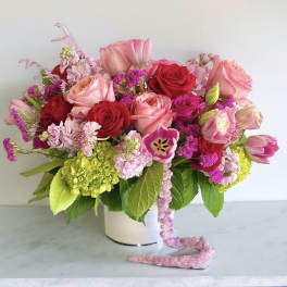 Pink and red rose bouquet in a white vase with mixed blooms