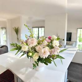Pastel floral arrangement in a white vase on a table