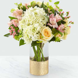 Bouquet of white hydrangea, pink alstroemeria, and cream roses in a glass vase